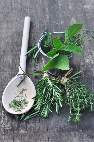 herbes aromatiques et cuillère en bois sur planche