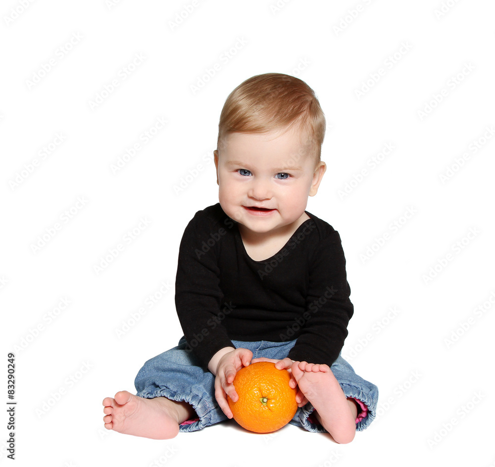 smiling baby sits and holds orange in hands smiling baby sits and holds orange in hands