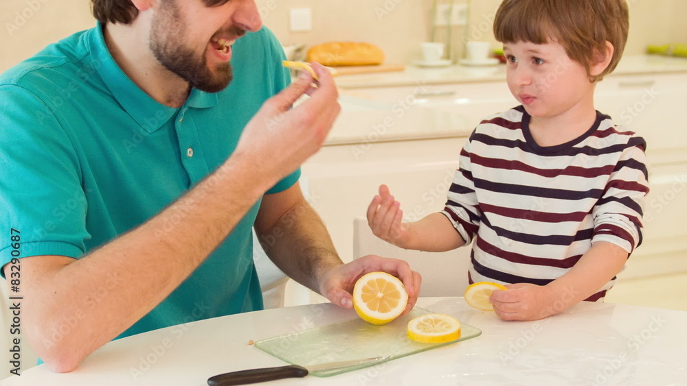Son and dad eating lemon together Son and dad eating lemon together