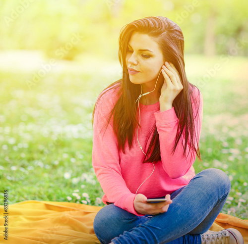 Female student girl outside in park listening to music on headph photo