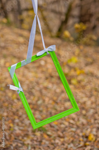 Green photoframe hangs on tree autumn background
