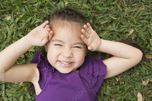 A girl lyiing on the grass with her hands by her head, laughing.  photo