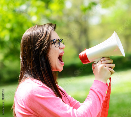 Portrait of middle aged woman shouting using megaphone against a