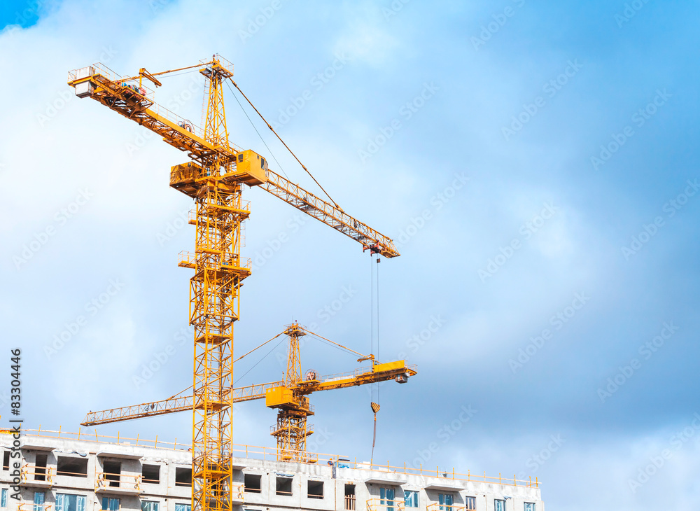 Yellow cranes work in modern houses massive