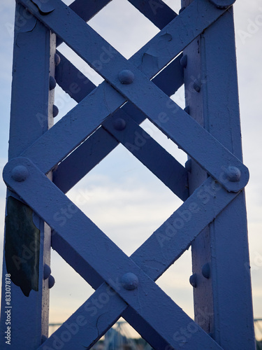 Detail of painted riveted bridge against blue sky.