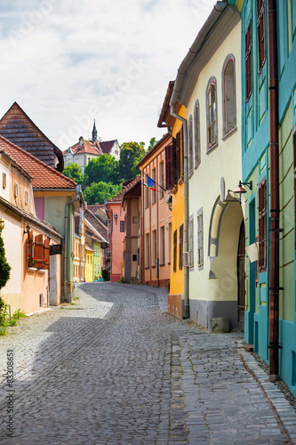 Stone paved old street with colored houses from Sighisoara © PixAchi