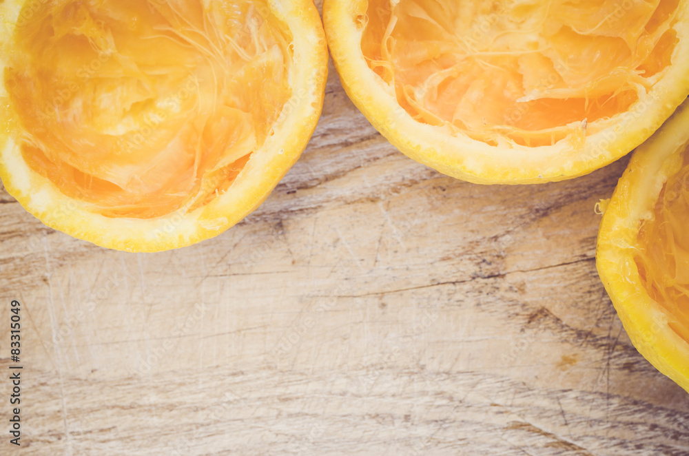 half cut squeezed oranges on a wood background