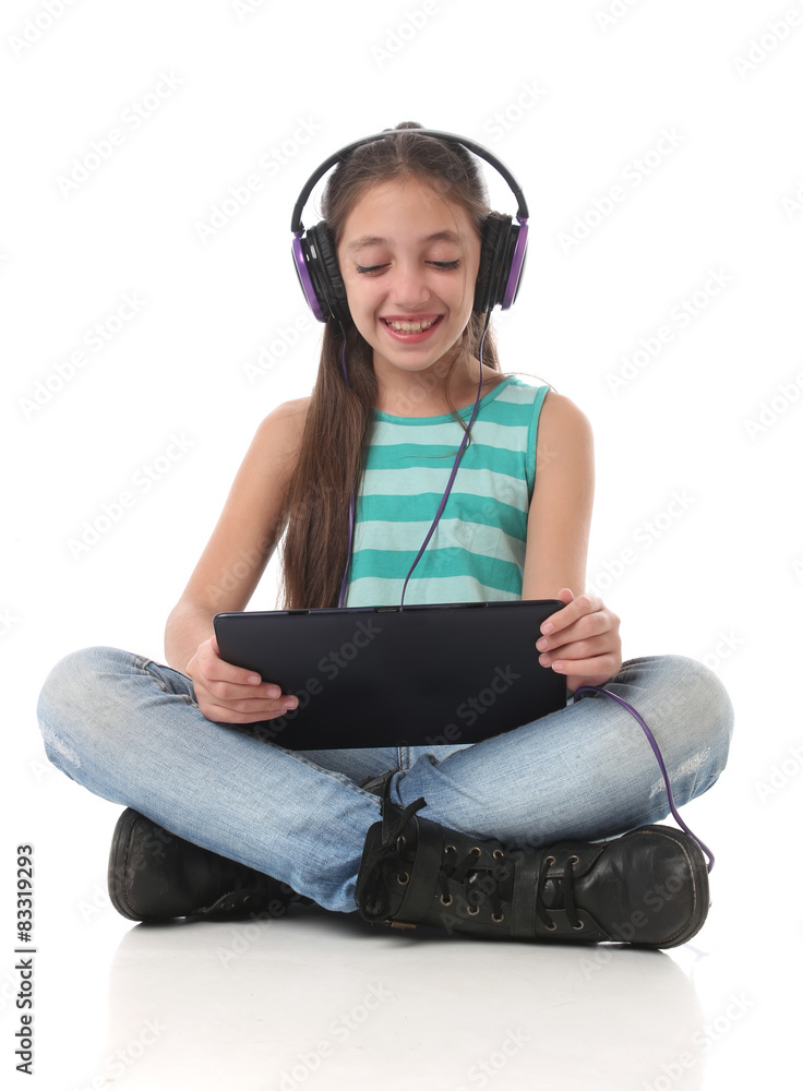 Beautiful pre-teen girl using a tablet computer and headphones. Beautiful pre-teen girl using a tablet computer and headphones.