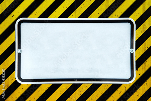 White sign on a concrete wall with black and yellow stripes
