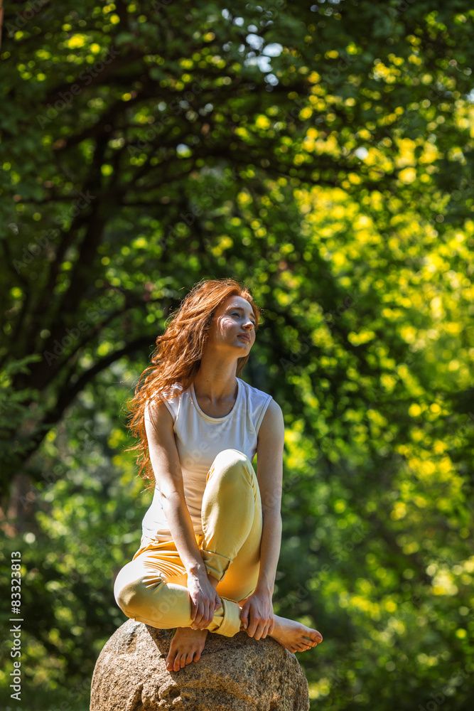 Red hair woman sitting on grass at the park 