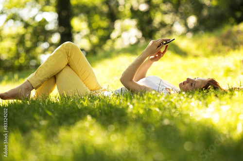 Woman  using a smart phone  at the park.Doing selfie.