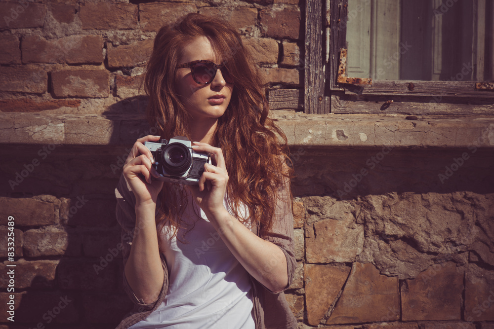 Woman standing by the wall and holding retro camera