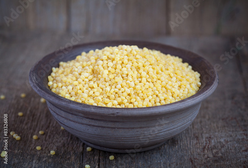Dry Israeli couscous ptitim in a clay bowl on wooden table