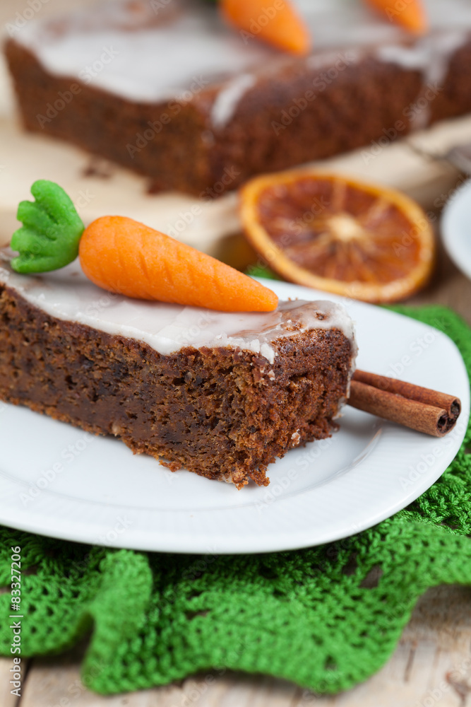 A piece of carrot cake with nuts, decorated with marzipan carrot A piece of carrot cake with nuts, decorated with marzipan carrot