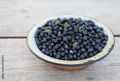 Ripe wild blueberries in a old bowl on the table, closeup