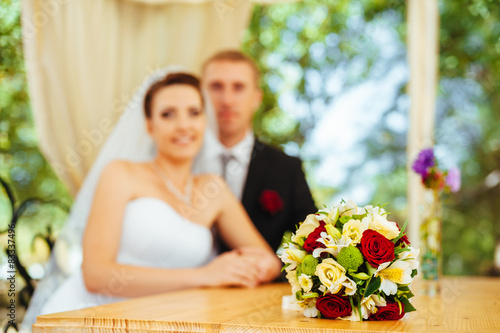 Bride and groom posing at the decorated banquet table in the