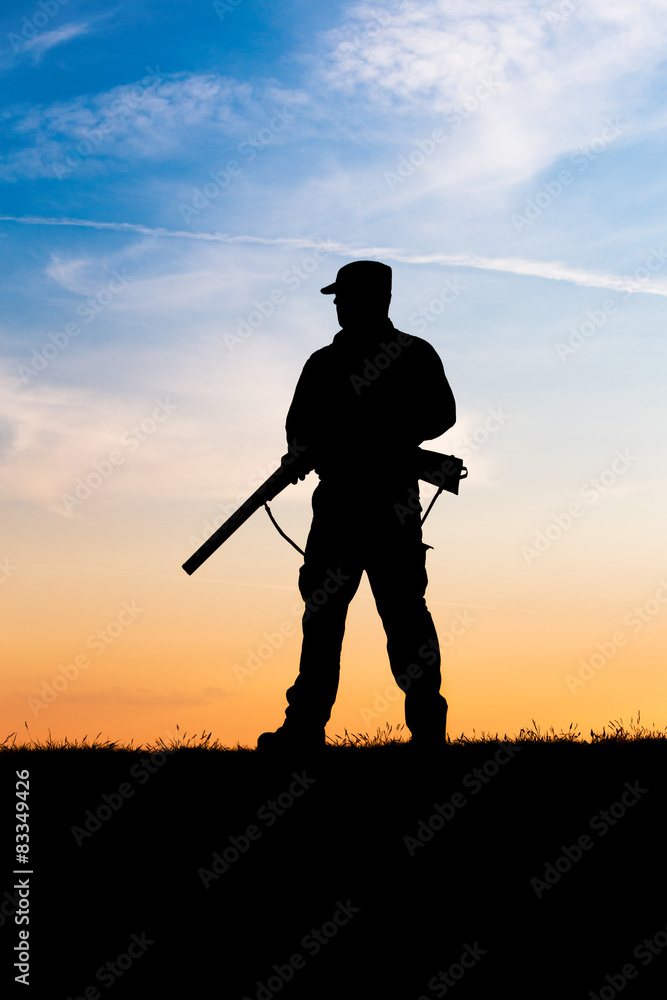 Hunter with shotgun in sunset