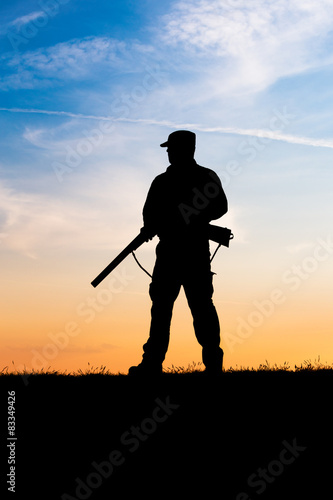 Hunter with shotgun in sunset