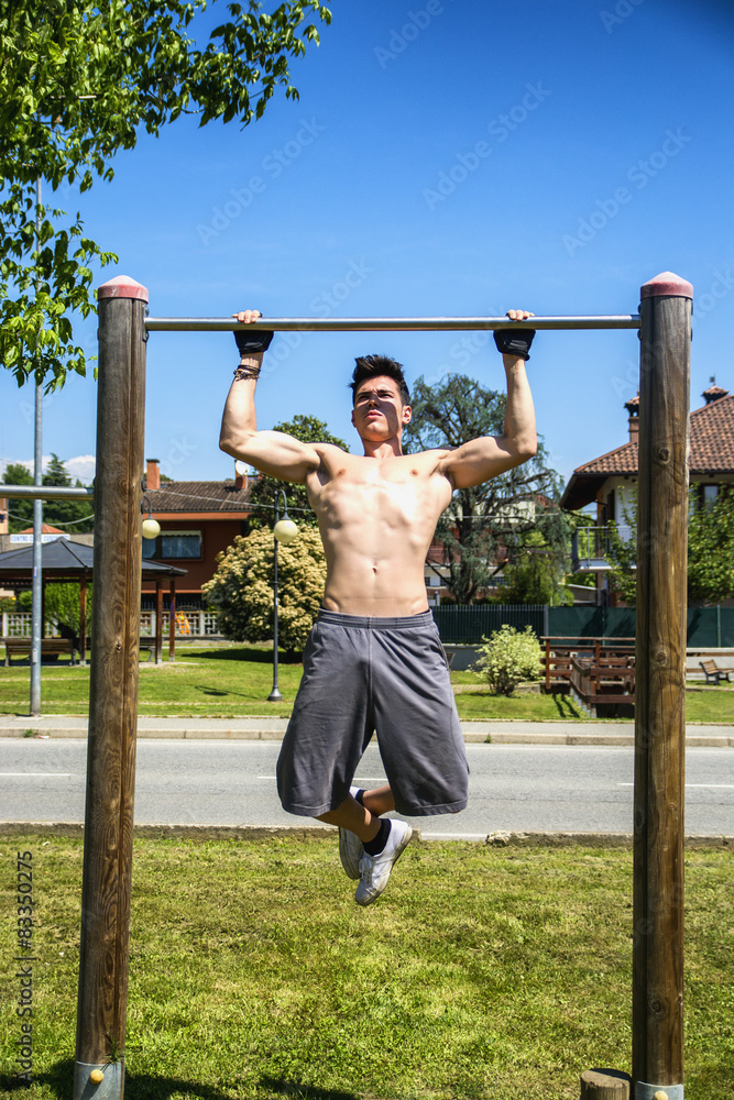 Attractive shirtless young man exercising outdoor in city park