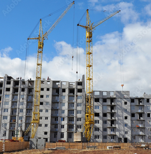 Building cranes and building under construction with people 