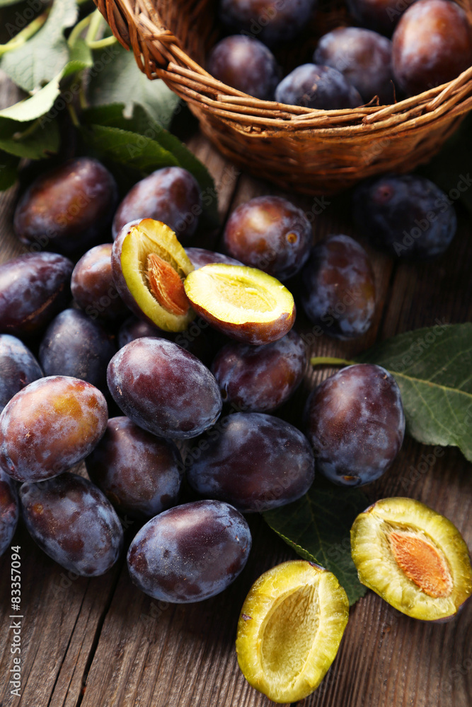 Fototapeta premium Fresh plums on brown wooden background