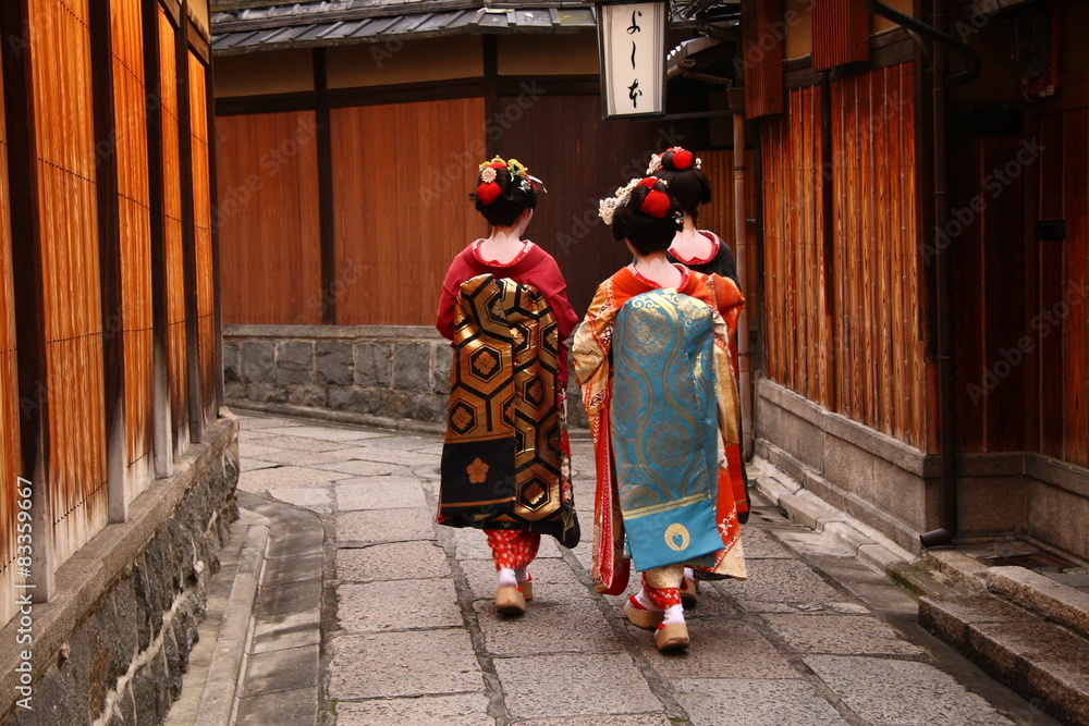 Naklejka premium Trzy gejsze chodzące po ulicy Gion (Kioto, Japonia)