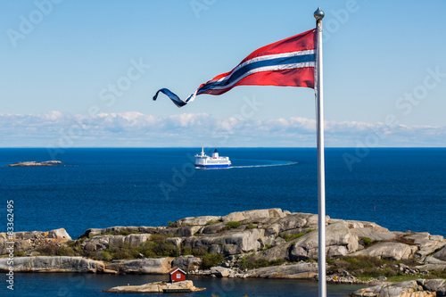 Norwegian flag with a small red cabin and an unmarked ferry photo