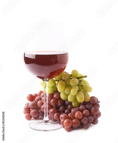 Glass of red wine next to a branch of grapes