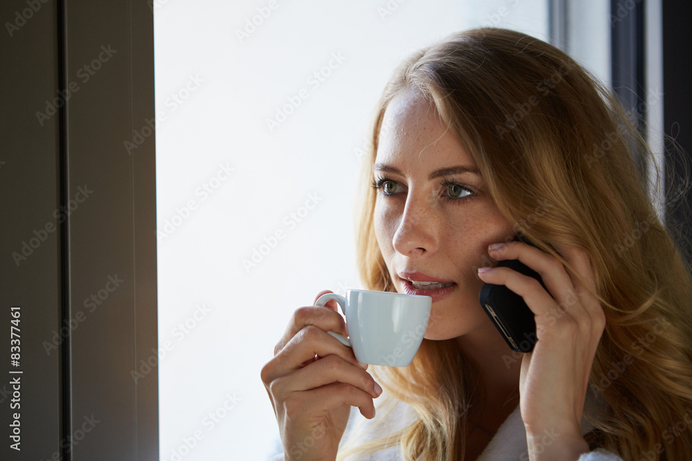 junge frau trinkt kaffee und telefoniert am fenster junge frau trinkt kaffee und telefoniert am fenster