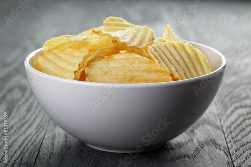 rippled organic chips in white bowl on wooden table
