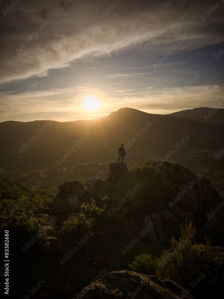 Fototapeta premium Hombre en lo alto de la montaña contempla la puesta de sol 2