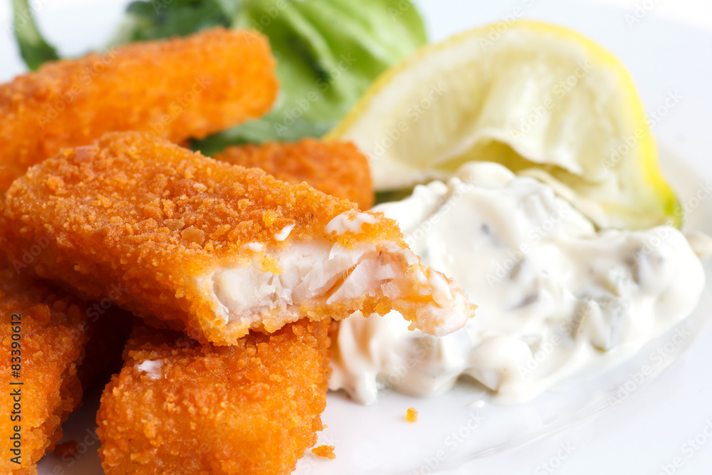 Half eaten fish fingers with lemon and tartar sauce. Half eaten fish fingers with lemon and tartar sauce.