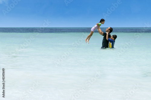 Man throwing her daughter on beach © Creativa Images
