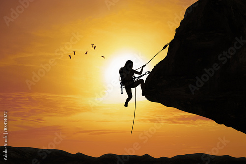 Silhouette of woman climbing on rock
