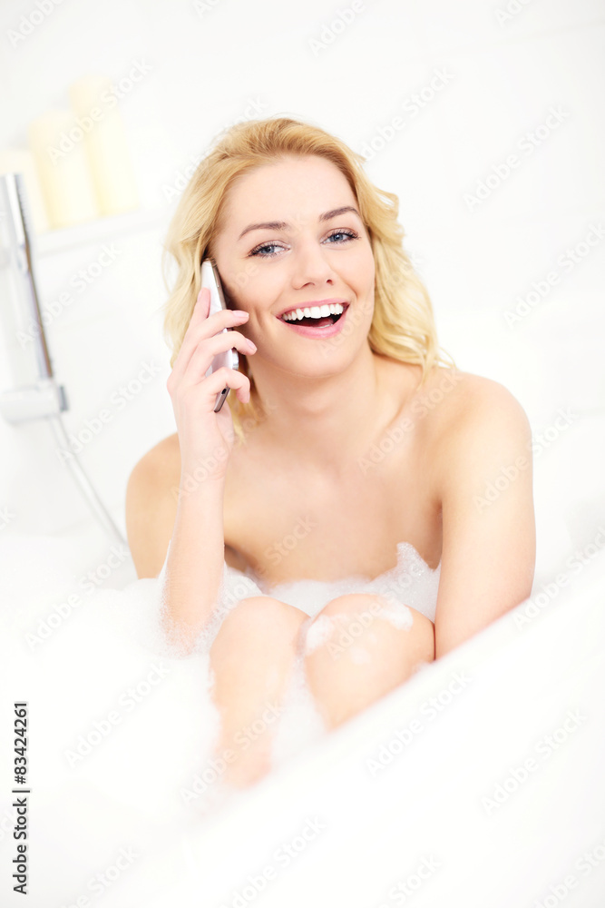Naklejka premium Woman talking on phone when taking a bath