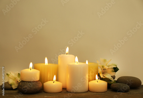 Beautiful composition with candles and spa stones on light background