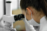 Female scientist looking through a microscope in laboratory