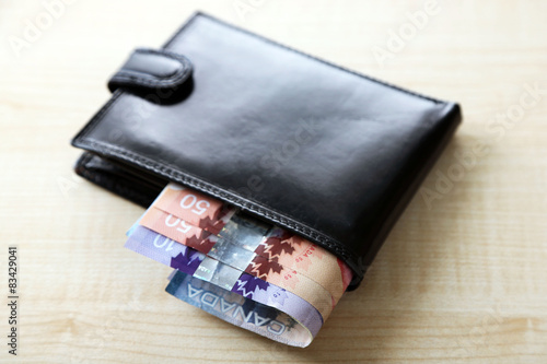 Male wallet with Canadian dollars on wooden table
