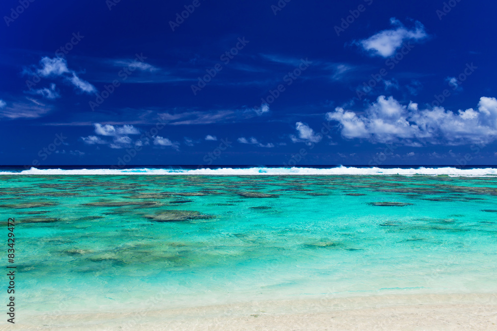 Tropical beach with coral reef and surf waves on Cook Islands