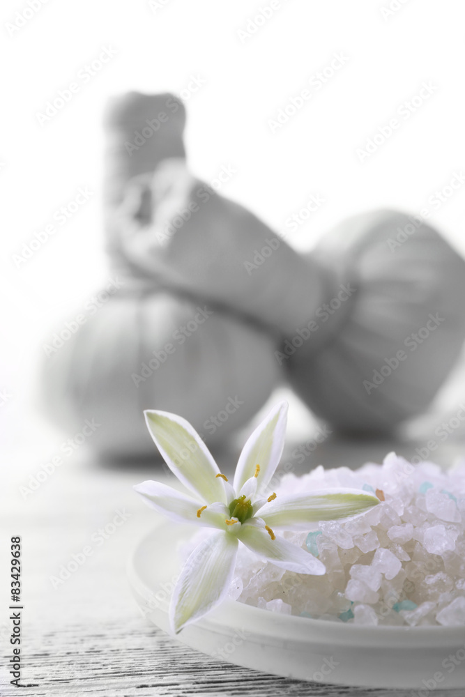Sea salt, flowers and spa treatment on color wooden table, on light background Sea salt, flowers and spa treatment on color wooden table, on light background