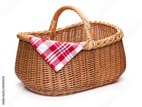 Wicker picnic basket with red checked napkin.