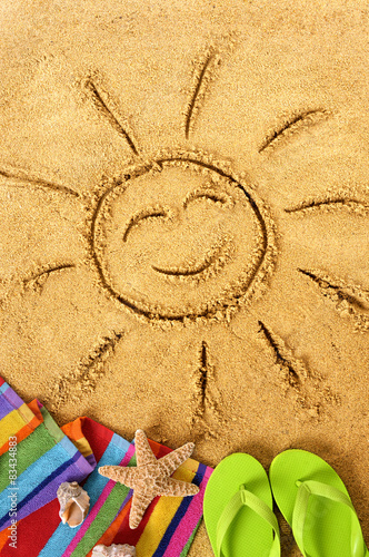 Summer beach smiling sun happy smiley face drawing drawn in sand with accessories holiday vacation photo vertical