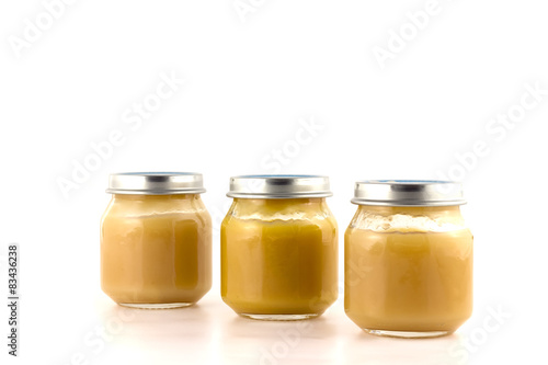 Three glass jars of baby puree fruit stand nearby