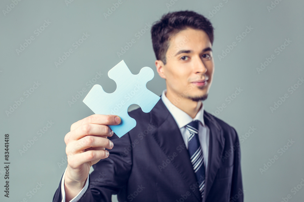 Young businessman holding piece of a puzzle Young businessman holding piece of a puzzle
