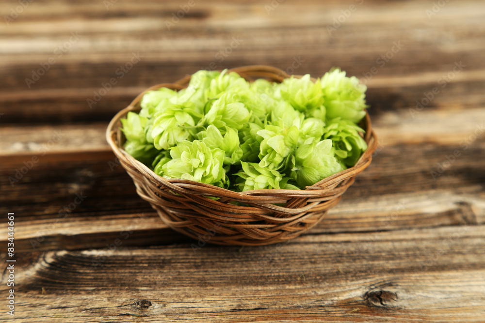 Hops in basket on brown wooden background Hops in basket on brown wooden background