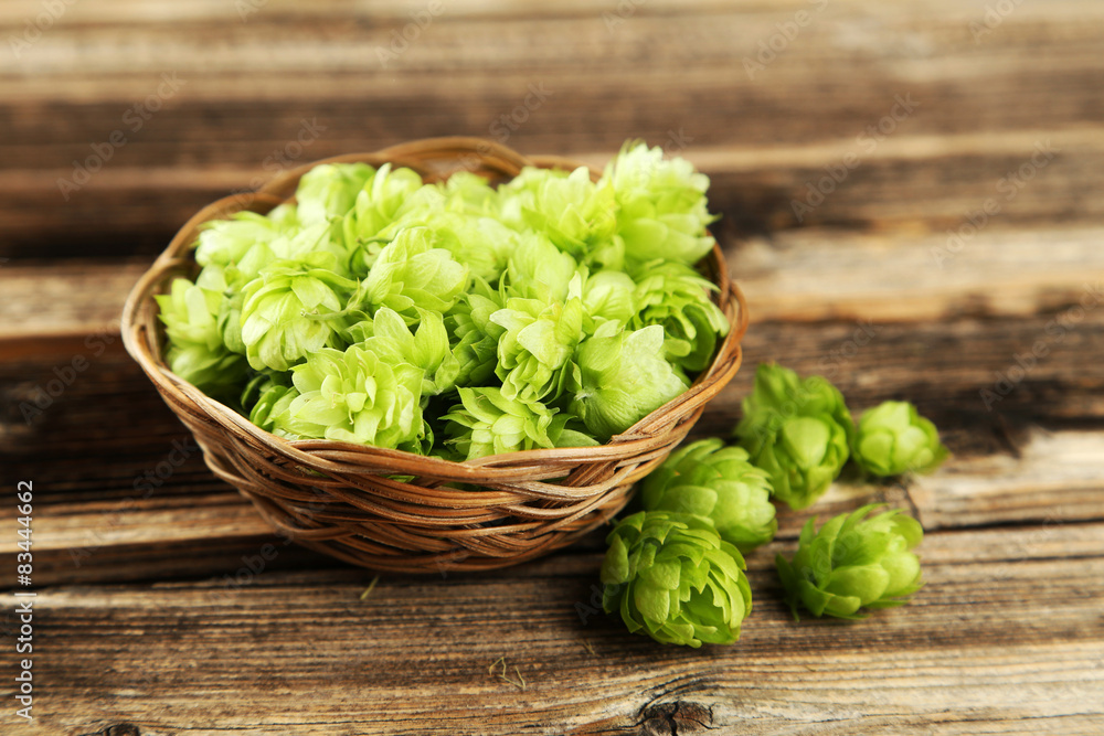 Hops in basket on brown wooden background Hops in basket on brown wooden background