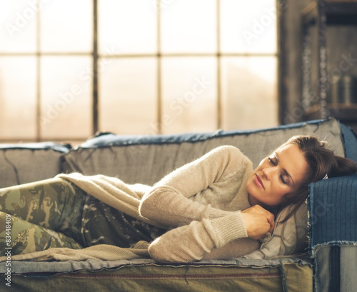 Billede på lærred Woman napping on a sofa in a city loft