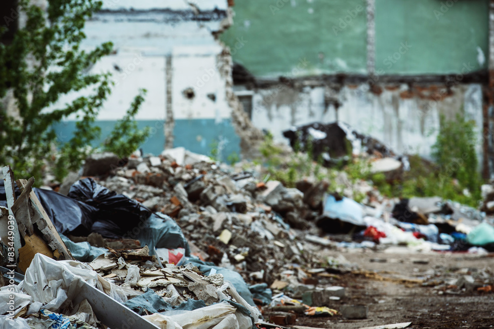Fototapeta premium A garbage dump and a building with ruined brick walls
