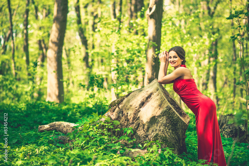 Woman in long red dress walking in the forest