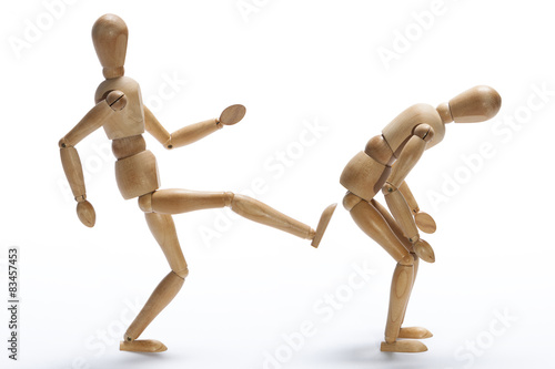 Wooden mannequin kicking in the backside to other